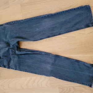 Grå tapered jeans från H&M - Säljer ett par grå jeans från H&M med relaxed fit och avsmalnande ben. Jeansen har justerbar midja och klassiska bakfickor. Perfekta för dig som gillar en avslappnad men ändå snygg stil.