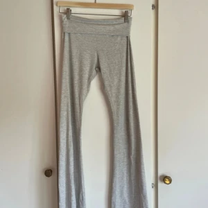 Grå bootcut mjukisbyxor - Superbekväma grå mjukisbyxor med bootcut och låg midja. Byxorna är i mjukt bomullsmaterial och har en bred linning som sitter skönt. Perfekta för en chill vardagslook eller när du bara vill vara extra comfy.