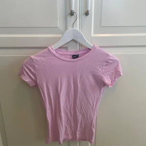 Ljusrosa topp från Gina Tricot XS - Supersöt ljusrosa topp från Gina Tricot i storlek XS. Modellen är enkel med rund halsringning och korta ärmar. Tillverkad i mjuk bomull som känns skön mot huden. Perfekt att matcha med jeans eller kjol. 