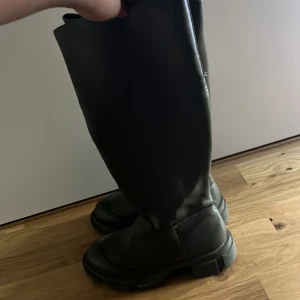 Gröna höga boots i skinnimitation - Snygga gröna höga boots med chunky sula och rund tå. Tillverkade i skinnimitation och perfekta för att lyfta din höst- eller vinterstil. Klassisk och stilren design som passar till många outfits.