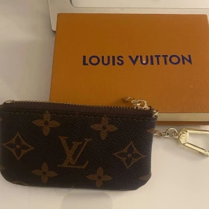 Brun monogram plånbok - Säljer en snygg liten plånbok i klassiskt brunt monogrammönster med guldiga detaljer och dragkedja. Perfekt för kort, mynt eller nycklar. Ej äkta 💗 kan sälja för 150kr vid snabb affär/köp 💗💗