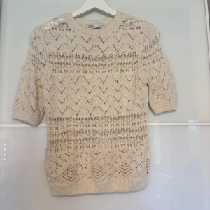 Beige stickad topp från Zara - Superfin beige stickad topp från Zara med korta ärmar och snyggt hålmönster i zigzag. Perfekt till vår och sommar, lätt att styla med både jeans och kjol. Mjuk och luftig känsla, passar dig som gillar en chill men ändå trendig look.