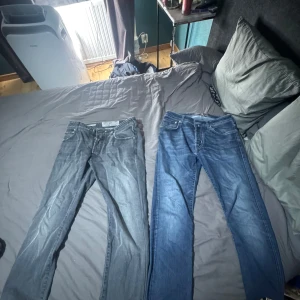 Jacob Cohën jeans i grått och blått - Två par snygga Jacob Cohën jeans, ett par i grå tvätt och ett i klassisk blå denim. Båda har raka ben, femficksmodell och tydliga kontrastsömmar. Tillverkade i bomull med exklusiv känsla och patch bak i midjan. Perfekta för dig som gillar stilrena och tidlösa jeans.