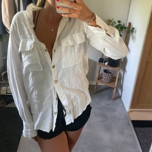 Vit linneskjorta med fickor - Säljer en vit skjorta i linne med två stora bröstfickor och snygga knappar framtill. 