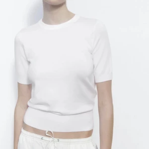 Vit stickad ribbad topp tshirt Zara - Superfräsch vit topp från Zara med rund halsringning och korta ärmar. Modellen är ribbad och sitter snyggt figurnära utan att vara för tight. Se defekter på bild 4 och 5. Därav billigt pris men märks inte mycket och går säkert att sy igen.