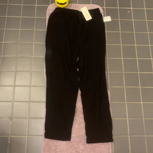 Svarta linnebyxor med snörning - Passar S-MSvarta mjukisbyxor från PanChaoHang med elastisk midja och snörning. Byxorna har raka ben och är tillverkade i ett mjukt bomullsliknande material. Perfekta för en chill och avslappnad stil.
