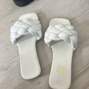 Vita flätade sandaler i storlek 36 - Snygga vita sandaler med breda, flätade remmar och fyrkantig tå. Platt sula och öppen design gör dem perfekta för varma dagar. Tillverkade i syntetmaterial med stilren look som passar till allt.
