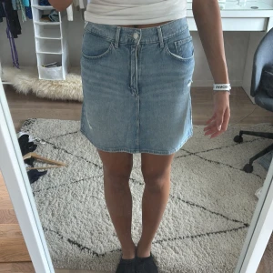 Ljusblå jeanskjol H&M - Ljusblå jeanskjol i klassisk femficksmodell med råa slitningar framtill. Kjolen är kort och har en lätt A-linjeformad passform. Perfekt till sneakers eller boots för en chill look. Bälteshällor och dragkedja framtill. Sitter som en XS
