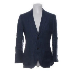 Mörkblå linnékavaj från Bläck - Snygg mörkblå kavaj från Bläck i 100% linne med skräddad passform. Klassisk design med två knappar framtill, fickor och slits bak. Perfekt för dig som gillar stilrena och luftiga plagg med skandinavisk känsla. Nypris 1999kr 