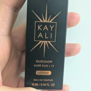 Kayali Oudgasm Café Oud Intense 10ml - Kayali Oudgasm Café Oud Intense är en lyxig parfym i svart, kantig flaska med gulddetaljer. Doften har noter av cappuccino, geranium, ros, vit mysk, vanilj och oud. Flaskan rymmer 10 ml och har en exklusiv vibe med elegant design. Endast provat. Förhandlar ej med priset.