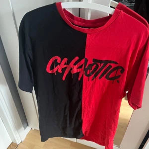 Röd & Svart T-Shirt - En T-shirt från Black Squad. Delad design i svart och rött. Trycket 'CHAOTIC' framtill i graffiti-stil. Storlek M 🍒