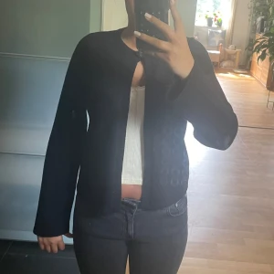 Svart kofta med knapp - Snygg svart kofta med rund halsringning och en enkel knapp framtill. Koftan är långärmad och har en clean, minimalistisk look som passar perfekt till jeans eller kjol. Mjuk och skön, perfekt för lager-på-lager under kyliga dagar.