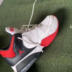 Nike Air Jordan 23 sneakers vit/röd/svart - Snygga Nike Air Jordan sneakers i vitt, svart och rött med klassisk Jumpman-logga och siffran 23 på plösen. Skorna har snörning, platt sula och är tillverkade i skinn med detaljer i syntet. Perfekta för dig som gillar streetstyle och basketinspirerad look.