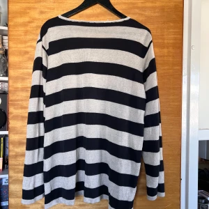Randig oversized tröja - Oversized långärmad tröja med breda svarta och vita ränder. Tröjan har en avslappnad passform och är tillverkad i ett tunt, stickat material. Går att passa med många olika stilar, tunn och sval såhär i sommar värmen