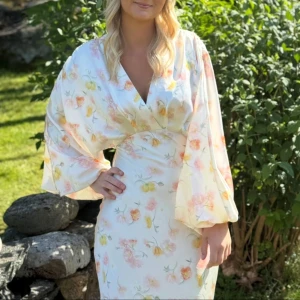 Vit långklänning med blommigt mönster - Superfin långklänning från ginatricot som inte kommer till användning mer. Endast använd på midsommar en gång, i nyskick! Perfekt för sommarens alla tillfällen. Nypris 699