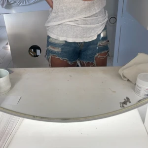 Blåa slitna jeansshorts Pull&Bear - Säljer ett par blåa högmidjade jeansshorts från Pull&Bear med råa, fransiga kanter och flera slitningar framtill. Klassisk femficksmodell med knapp och dragkedja. Perfekta för sommaren och ger en cool, avslappnad vibe.