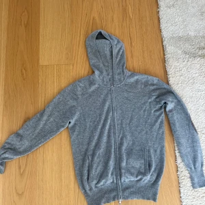 Grå sfot goat hoodie med mockadetaljer - Grå soft goat Kashmir Hoodie med mockdetaljer. Köpt för ca 3500.