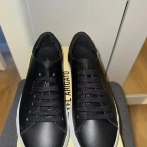 Svarta sneakers Axel Arigato skinn - Stilrena svarta sneakers från Axel Arigato i skinn med klassisk låg profil och vita sulor. Köpte till min syster för några veckor sedan men tyvärr passar dem inte henne🌸  Man får med både Axel arigato påse och skokartong!