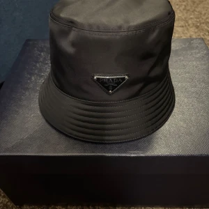 Prada Bukcet Hat - Prada Re-Nylon Bucket Hat, storlek M. Färg: svart. Kommer med box, dustbag. I  nyskick 