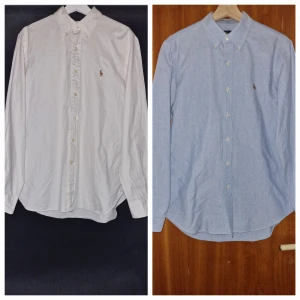 Två skjortor från Polo Ralph Lauren - Säljer två stilrena skjortor från Polo Ralph Lauren. En vit och en ljusblå, båda med klassisk krage och broderad logga på bröstet. Skjortorna har långa ärmar och knappar framtill. Perfekta för en elegant look. Säljer båda för 700 kr. En för 300kr. Den blå är såld
