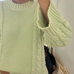 Ljusgrön stickad tröja - Säljer en mysig ljusgrön stickad tröja med flätstickat mönster på ärmarna och sidorna. Tröjan har en rund halsringning och långa ärmar, perfekt för kyligare dagar. Passar bra till både jeans och kjol. 🌿