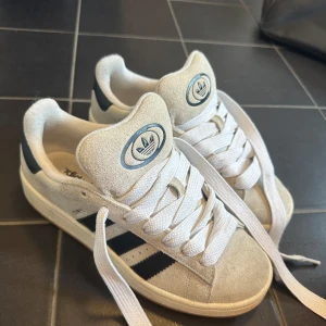 Adidas Campus sneakers i beige mocka - Snygga Adidas Campus sneakers i beige mocka med klassiska svarta ränder och vit snörning. I jättebra skick! Köptes i USA! 
