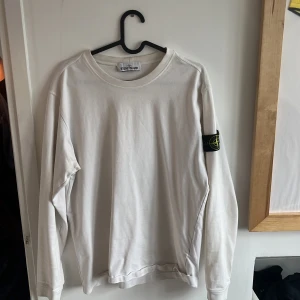 Stone Island crewneck - Säljer en stilren vit långärmad tröja från Stone Island. Tröjan har en klassisk rund hals och det ikoniska Stone Island-märket på ärmen. Perfekt för en avslappnad och trendig look.