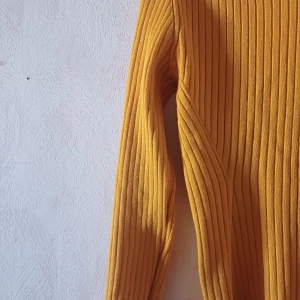 Gul ribbad tröja - Säljer en snygg gul ribbad tröja med långa ärmar. Perfekt för att lysa upp garderoben med en färgklick. Tröjan har en enkel och stilren design som passar till många olika outfits.