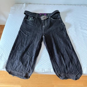 Svarta jeans - Säljer ett par svarta baggy jeans med bred passform och coolt vitt tryck på bakfickan. Byxorna har klassisk femficksdesign och dragkedja. Perfekta för dig som gillar streetwear. De är XL fast inte så baggy som jag ville, därför säljer de.