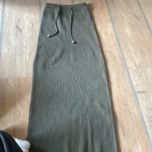 Olivgrön ribbad långkjol från Primark - Säljer en olivgrön ribbad långkjol från Primark med dragsko i midjan. Kjolen är mjuk och stretchig, perfekt för en avslappnad stil. Passar dig som gillar enkel och stilren design.