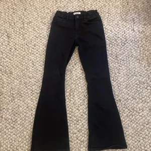 Svarta bootcut byxor från Lindex - Svarta byxor från Lindex i bootcut-modell med klassisk femficksdesign och knapp framtill. Byxorna har en något utsvängd passform nertill och är perfekta för dig som gillar en tidlös stil.