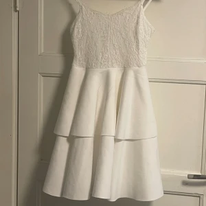 Vit klänning med spets och volang  - Den är bara använd en gång. Den är i storlek 13y. Skulle tro att den sitter som xxs