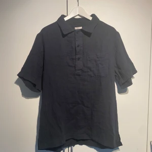 Kortärmad linneskjorta Studio Total - Studio Total kortärmad skjorta i svart färg. Enormt bekväm och perfekt inför sommaren. Luftig och rymlig. Storlek M. Sparsamt använd och i fint skick. Nypris 699kr. Fler bilder kan du få i DM. 