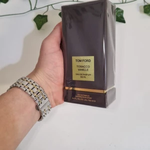 Tom Ford Tobacco Vanille Eau de Parfum 100 ml - Säljer en lyxig Tom Ford Tobacco Vanille Eau de Parfum i en elegant brun förpackning med guldiga detaljer. Flaskan innehåller 100 ml av denna ikoniska doft som kombinerar rika noter av tobak och vanilj för en sofistikerad och varm upplevelse.