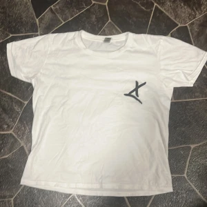 Vit t-shirt med tryck och grafiskt motiv - Vit t-shirt med svart grafiskt tryck på bröstet och stort konstnärligt motiv på ryggen med texten 'CONTROL ALL ROUND CREATIVITY DIFFICULTY EXECUTION'. T-shirten har rund hals och korta ärmar, perfekt för en avslappnad stil.