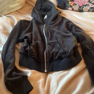 Svart hoodie från H&M - Säljer en svart hoodie från H&M med dragkedja och huva. Den har långa ärmar och en croppad passform. Perfekt för en avslappnad stil.