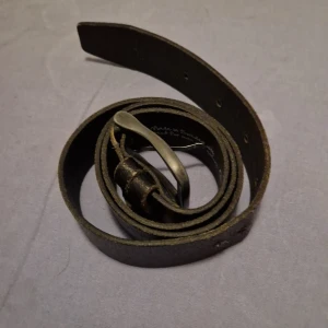 Svart bälte från RAGE - Snyggt svart bälte från RAGE. Bältet har en stilren design med en klassisk metallspänne. Perfekt för att komplettera din outfit med en touch av stil och hållbarhet. Det är i mycket bra skick💯