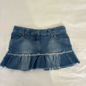 Jeanskjol med volang - Trendig jeanskjol i blå denim med volangdetalj och fransad kant. Jättesöt trendig jeanskjol  med låg midja och volanger 🩷  Storlek: Lappen är borta men skulle säga att den är strl 36 Midjemått: 39 cm Längd: 28 cm
