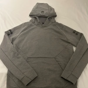 Sail Racing Hoodie - Säljer en stilren grå Sail Racing hoodie med svart tryck på både huvan och ärmarna.