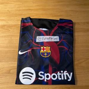 FC Barcelona hemmatröja 2022/23 - Säljer en FC Barcelona hemmatröja från säsongen 2022/23 med klubbmärke, Nike-logga och Spotify som sponsor. Tröjan är kortärmad och har ett randigt mönster i blått, rött och mörkblått. Perfekt för dig som älskar Barca!