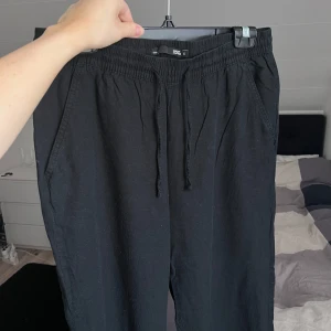 Svarta linnebyxor med resårmidja - Säljer ett par svarta linnebyxor med resårmidja och snörning. Byxorna har en avslappnad passform och är perfekta för en bekväm stil. De har sidofickor och är tillverkade i ett mjukt material. Sparsamt använda 💜 Önskar du veta exakta mått? Tveka inte att höra av dig!