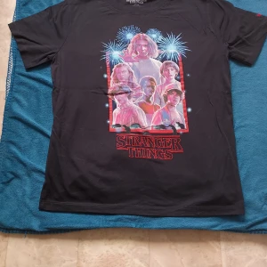 Stranger Things t-shirt - Helt ny, har enbart provat t-shirten. Mått: Längd = 64 cm och bredd = 51 cm. Skulle säga att det en en unisex modell men kommer inte ihåg om den marknadsfördes som det.