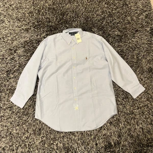Ljusblå oxfordskjorta från Ralph Lauren - Tja! Säljer en helt oanvänd skjorta från Ralph Lauren. Den har aldrig använts utan endast prövats en gång alltså är den helt ny. Inga defekter eller liknande framkommer på skjortan, modellen är i Oxford och regular. Nypris 1600kr. Pris kan diskuteras vid snabb affär!