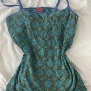 Blommig linnetopp från Björn Borg - Supersöt linnetopp från Björn Borg med blått blommönster på grön botten. Toppens kant är blå och den har smala axelband. Perfekt för dig som gillar färg och mönster! Materialet är mjukt och stretchigt, vilket gör den riktigt skön att bära.