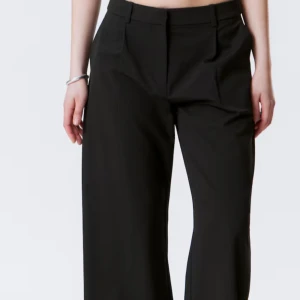 Svarta vida kostymbyxor - Snygga svarta kostymbyxor med vida ben och klassisk passform. Byxorna har hällor för bälte och pressveck framtill, perfekta för en clean och stilren look. Medelhög midja. Säljer då de är för små (har storlek M så skulle säga att de passar xs/S). Är osäker på märke men troligast H&M. Endast använd en gång till en begravning. 