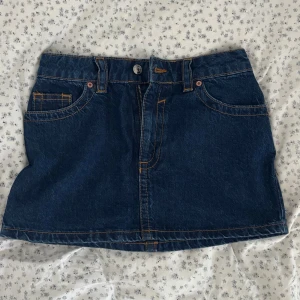 Lågmidjade jeanskjol  - Säljer en mörkblå lågmidjad jeanskjol från Asos design i storlek 34. Kjolen har knäppta fickor på baksidan som går att öppna💗