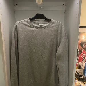 Grå sweatshirt från H&M Essentials - En stilren grå sweatshirt från H&M Essentials, relaxed fit med rund halsringning och långa ärmar. Perfekt för en chill och enkel look. Tillverkad i mjuk bomullsmix som känns skön mot huden. Storlek m. Knappt anvönd