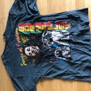 Bob Marley t-shirt med tryck - Cool t-shirt med stort färgglatt Bob Marley-tryck och texten 'Spirit of Freedom' på framsidan. T-shirten är mörkblå och har korta ärmar. Perfekt för dig som gillar reggae och vill sticka ut med en ikonisk look.