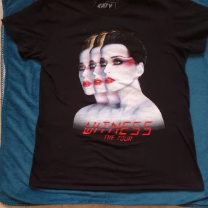 Katy Perry t-shirt - Katy Perry t-shirt från hennes Witness The Tour 2017-2018. Tryck på både fram- och baksida. Plaggets längd ca 69 cm och mått tvärs över bröstet ca 50 cm.