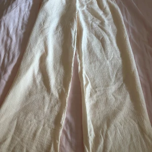 Vida ljusa byxor - Säljer ett par ljusa (cremefärgade), vida och tunna byxor med snyggt fall och lätt struktur. Perfekta för varma dagar och ger en chill vibe till outfiten. Byxorna har rak passform och är tillverkade i ett tunt, luftigt material. Byxorna hsr väldigt stretchig midja. 
